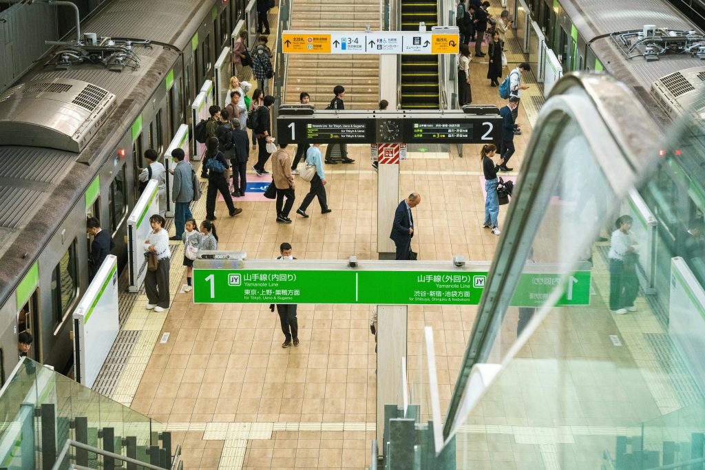 A bustling scene at a Tokyo train station with commuters boarding and alighting trains.